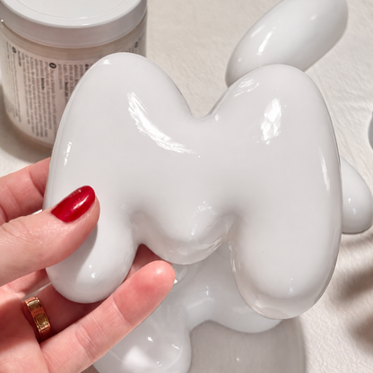 Close-up of a glossy white 3D bubble letter M showing its rounded ceramic-look finish