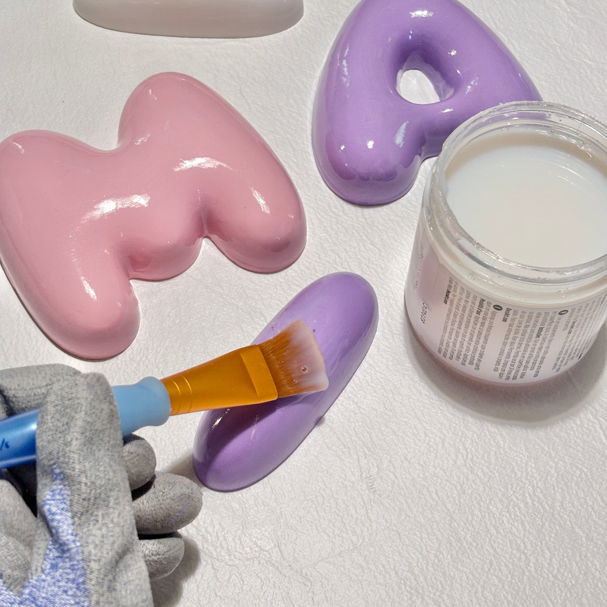 Applying a glossy ceramic-look coating to purple 3D bubble letters by hand