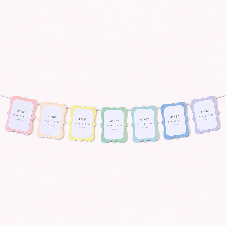 A pastel photo banner garland with seven scalloped rectangular frames in pastel rainbow colors strung along a white cord against a plain white background.
by The Homenko Studio, Calgary, Canada